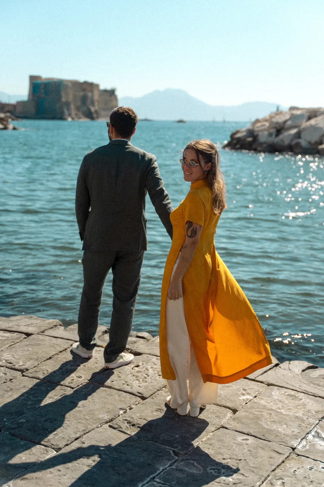 La sposa in abito giallo si volta sul lungomare di Napoli