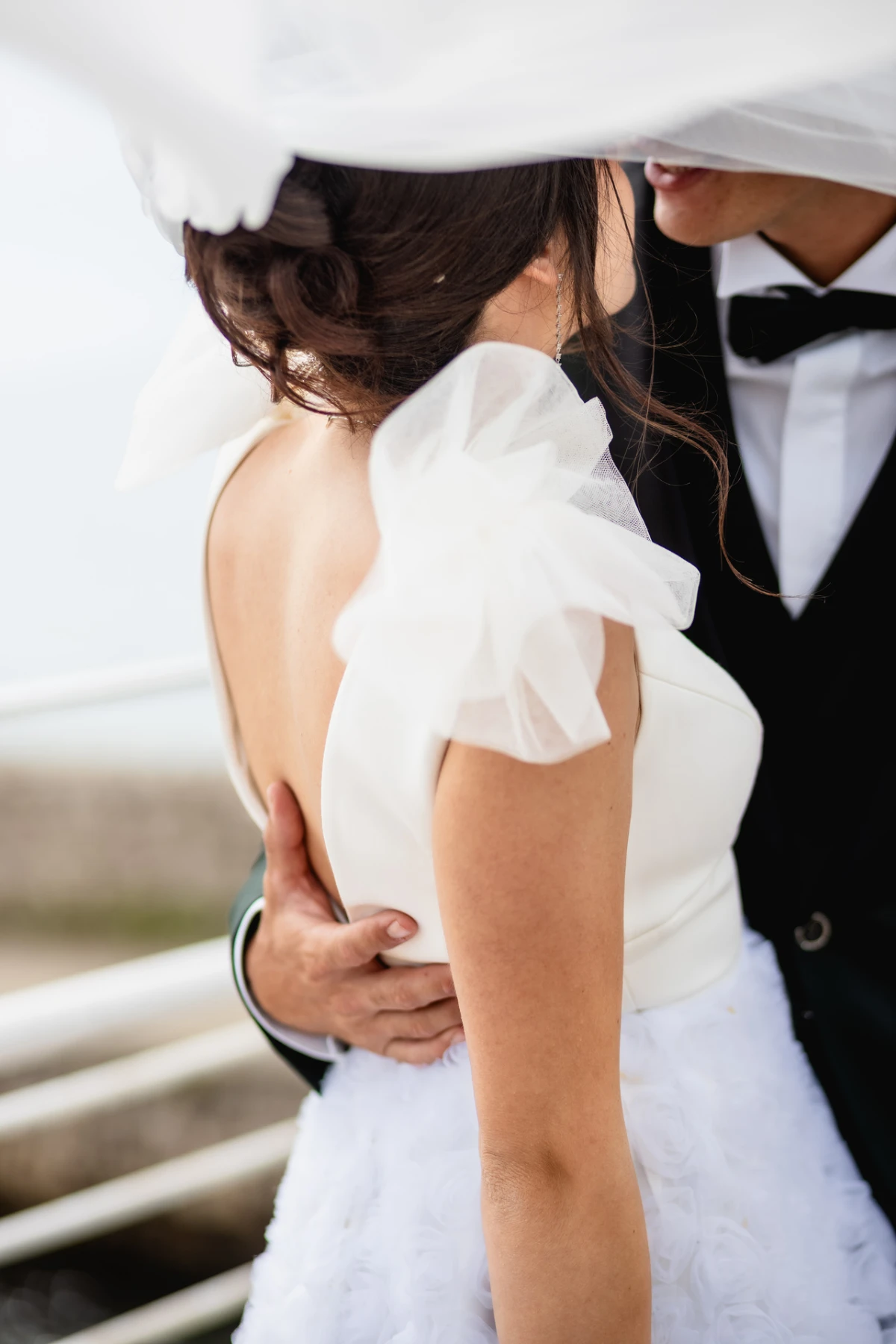 La sposa di spalle abbracciata allo sposo sotto il velo