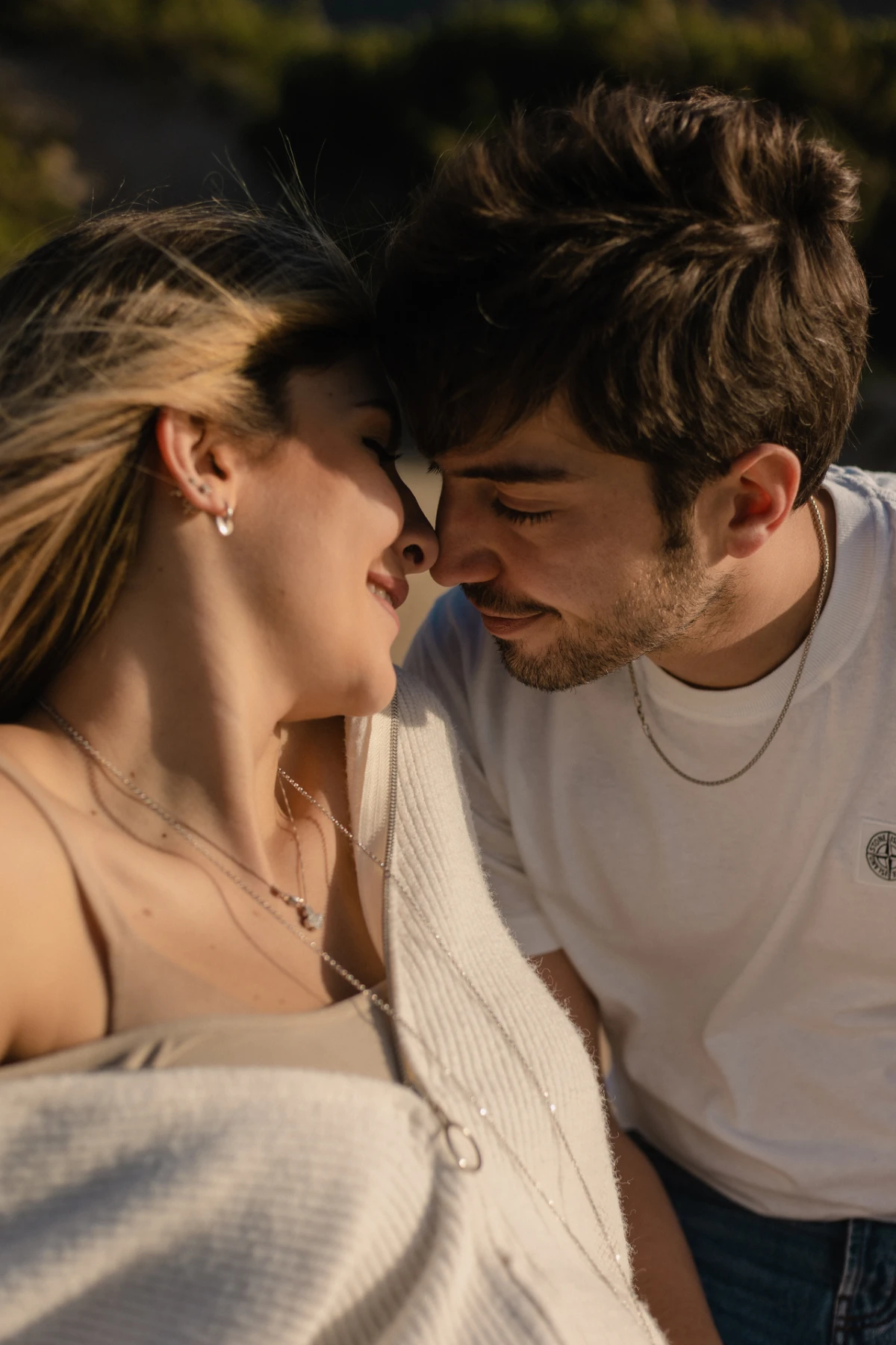 Una coppia, viso contro viso, sorride al sole
