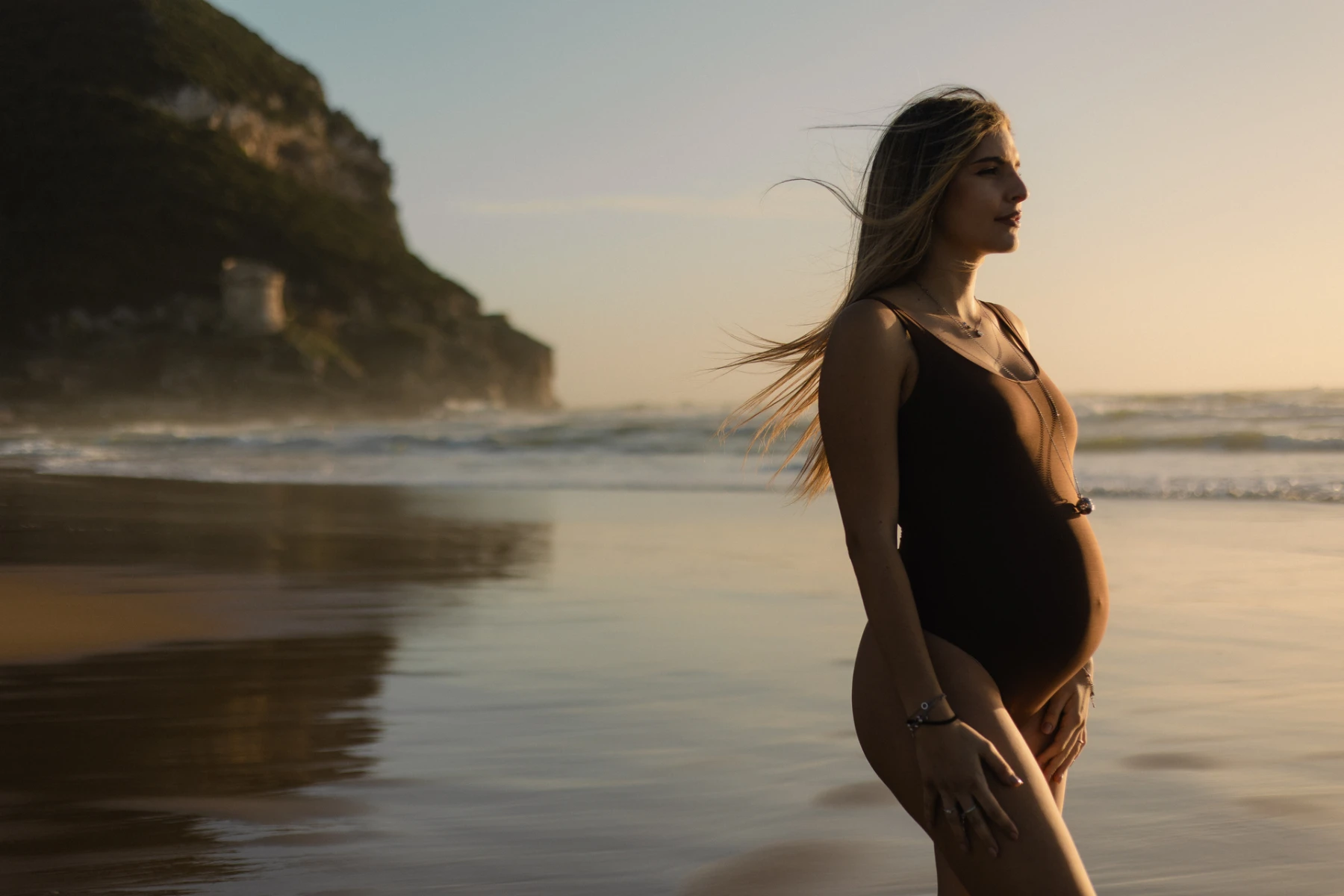 Una donna incinta sulla spiaggia al tramonto