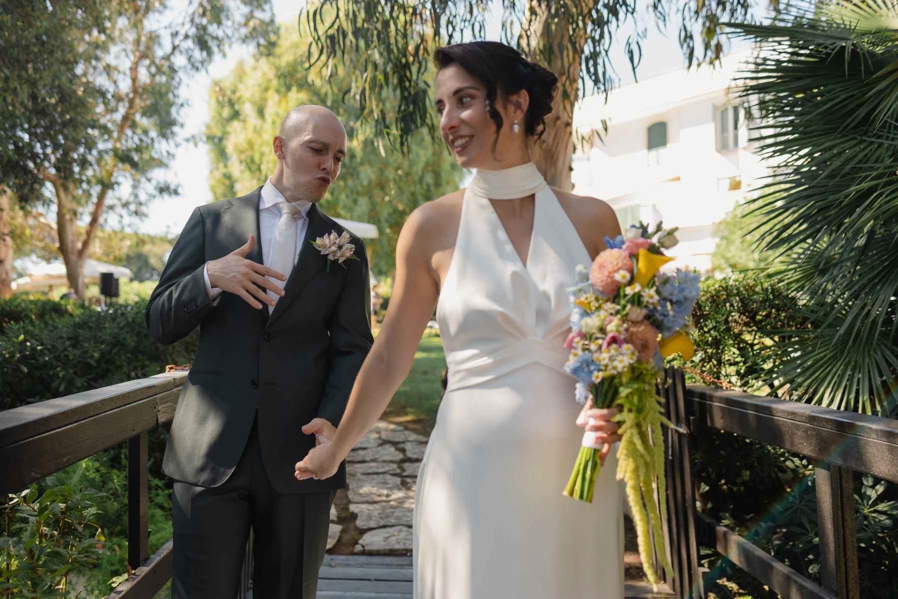 Lo sposo scherza mentre la sposa lo tira per mano sul ponticello
