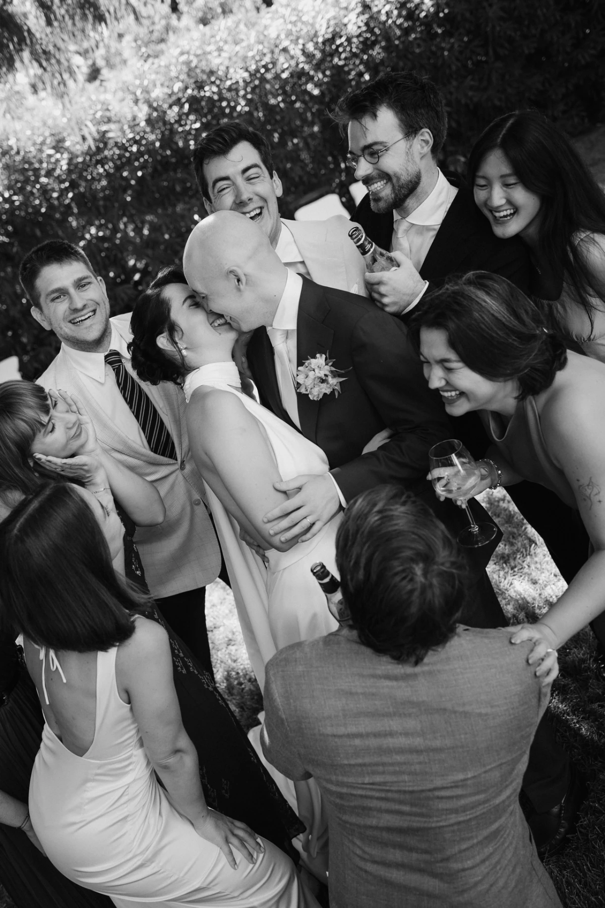 Gli amici abbracciano gli sposi ridendo, in bianco e nero
