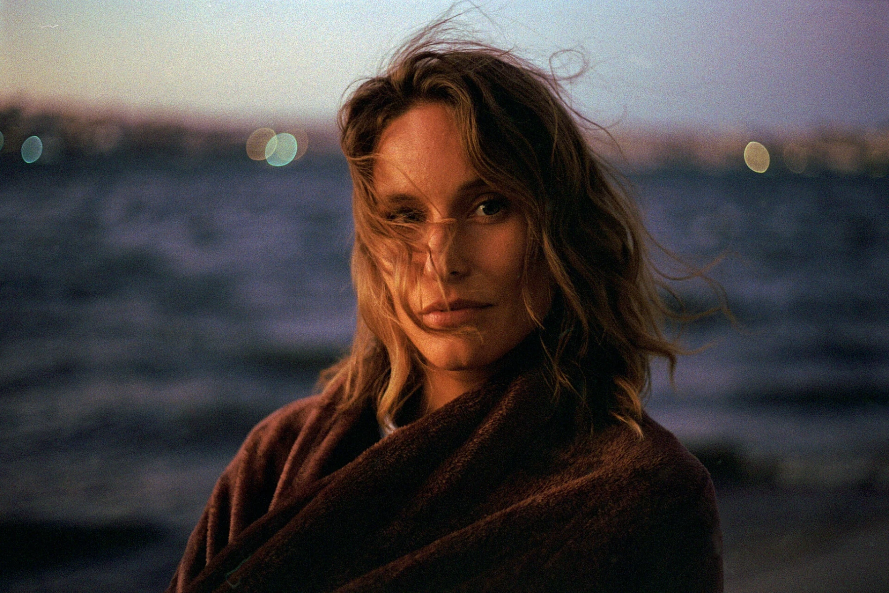Ritratto di Olly con i capelli al vento, al tramonto sul mare
