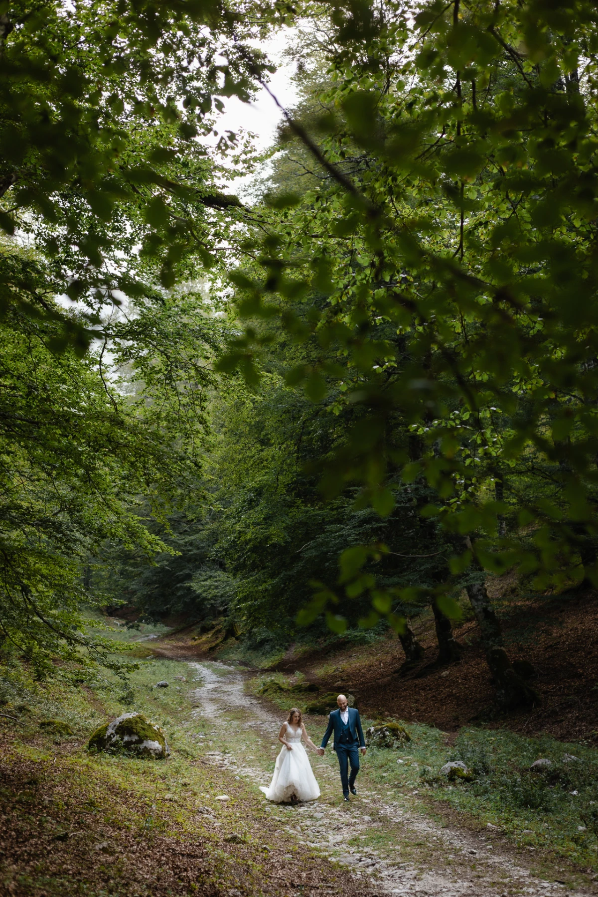 Gli sposi camminano su un sentiero nel bosco