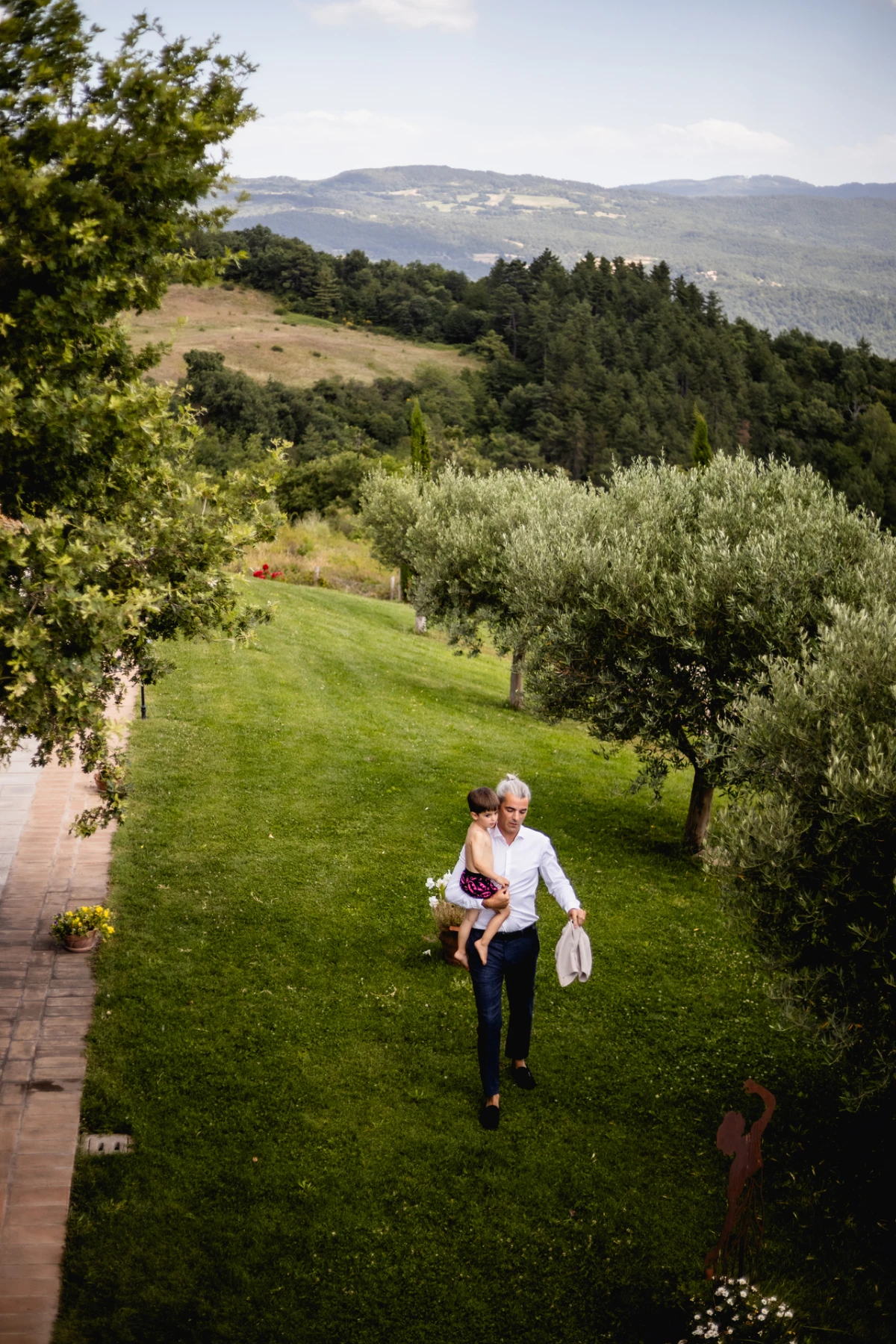 Gli sposi camminano sul prato tra gli ulivi, in Toscana